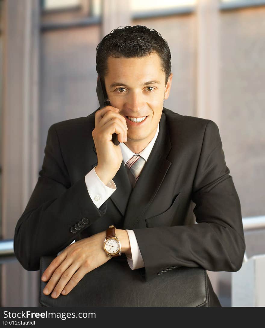 Businessman outside a modern building smiling with phone. Businessman outside a modern building smiling with phone.