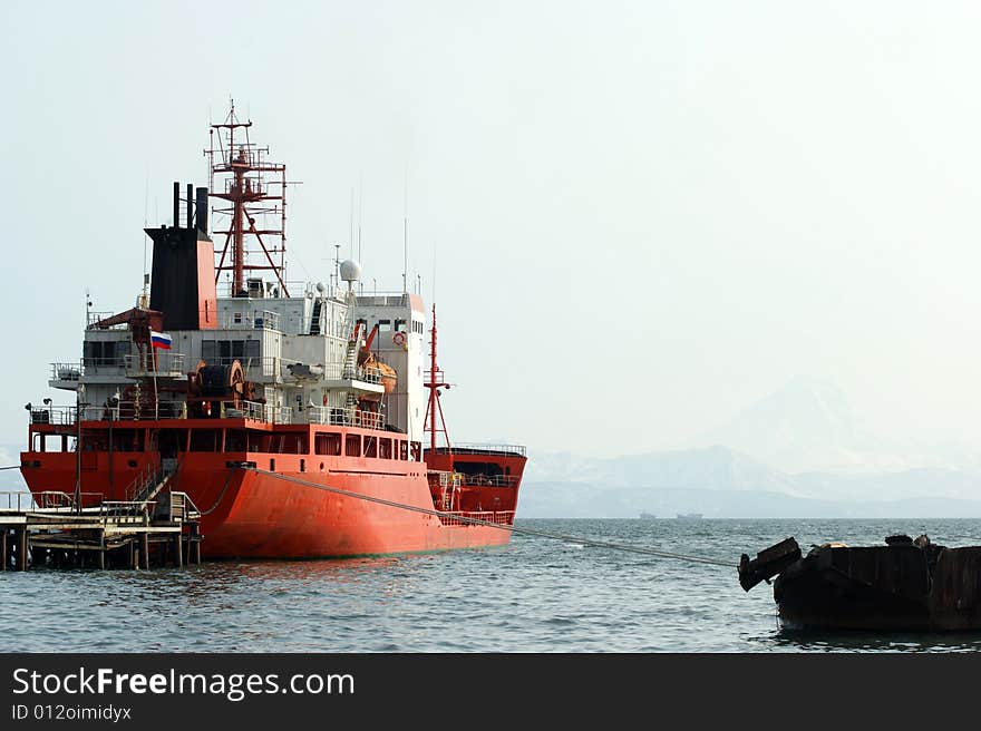 The red nave beside pier on background of the misty mountains. The red nave beside pier on background of the misty mountains.