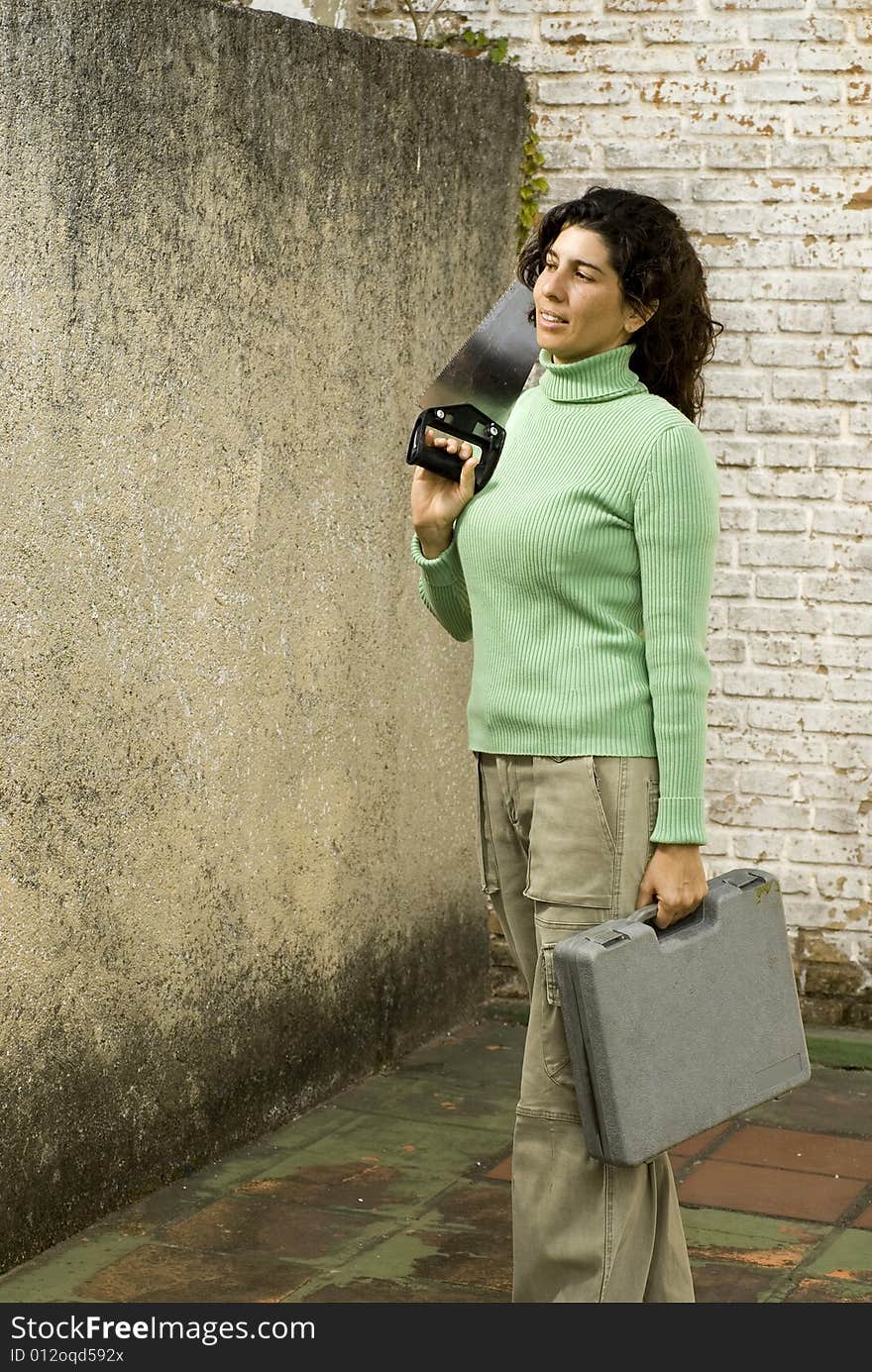 Woman stands while holding handsaw and toolkit. Vertically framed photo. Woman stands while holding handsaw and toolkit. Vertically framed photo.