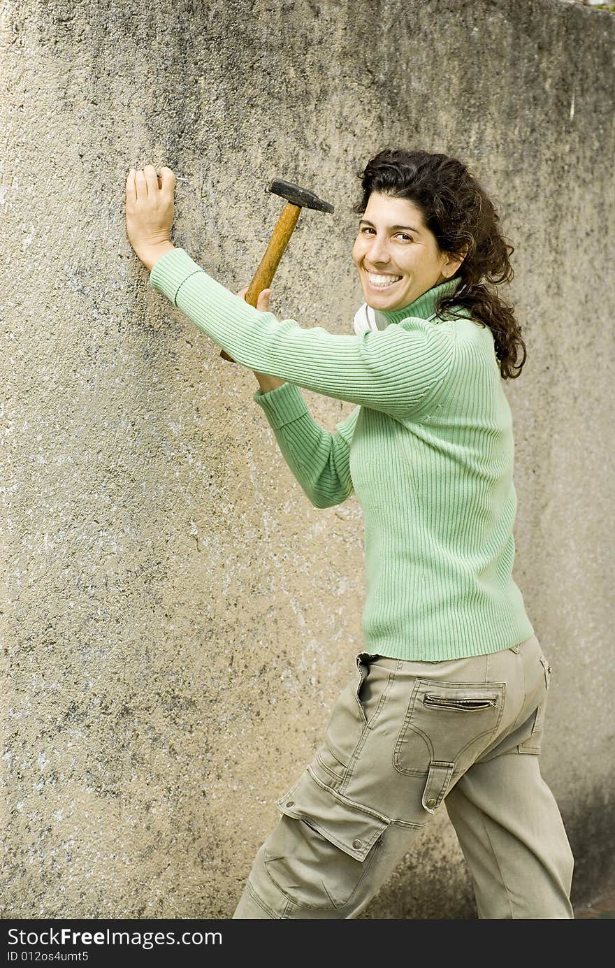 Smiling woman hammering a wall. Vertically framed photo. Smiling woman hammering a wall. Vertically framed photo.