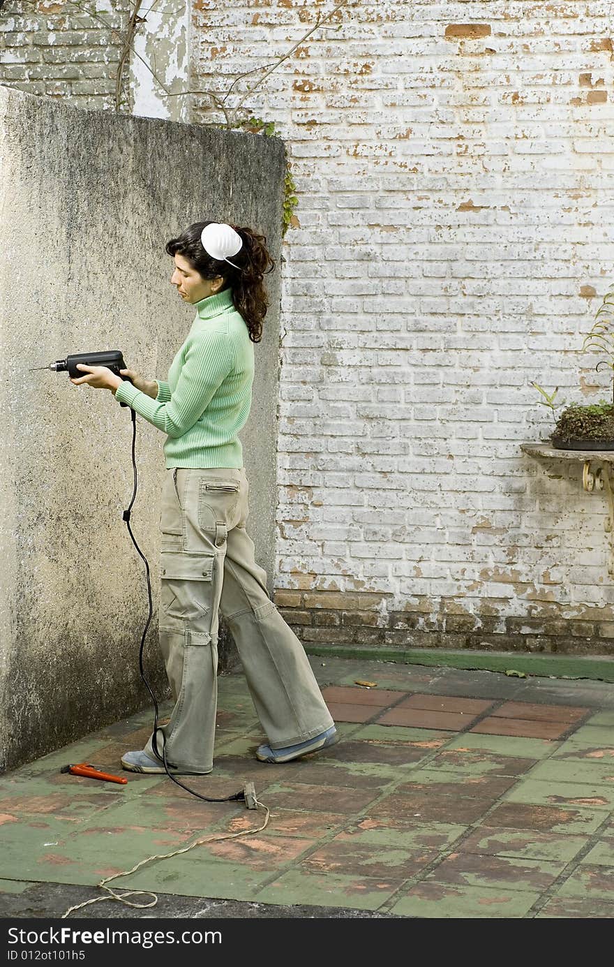 Woman drilling a wall. Vertically framed photo. Woman drilling a wall. Vertically framed photo.