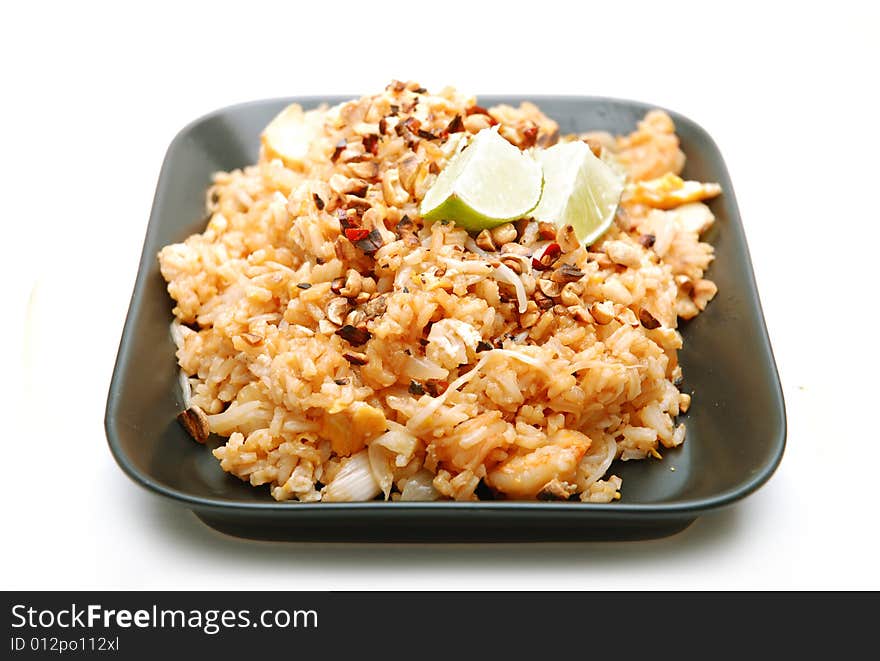 Asian rice dish served on black plate, isolated on white background.