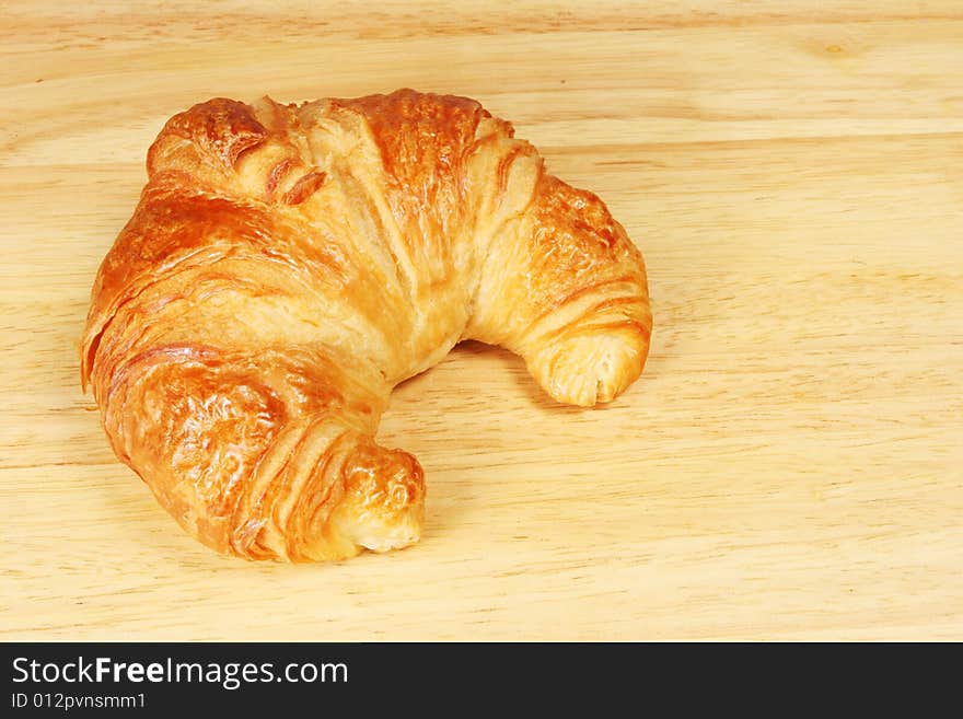 Single croissant on a bread board. Single croissant on a bread board