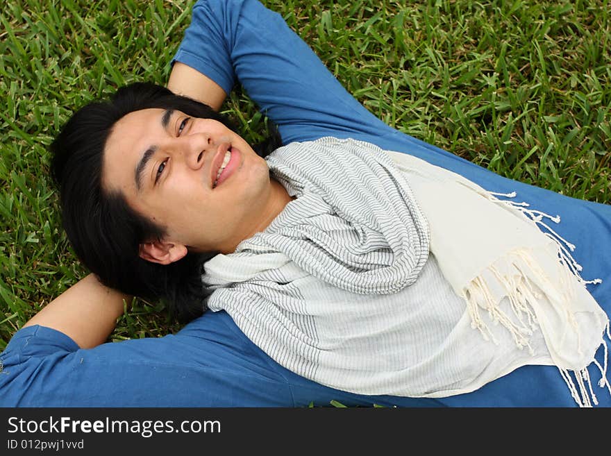 Young male laying spread out on the grass. Young male laying spread out on the grass.