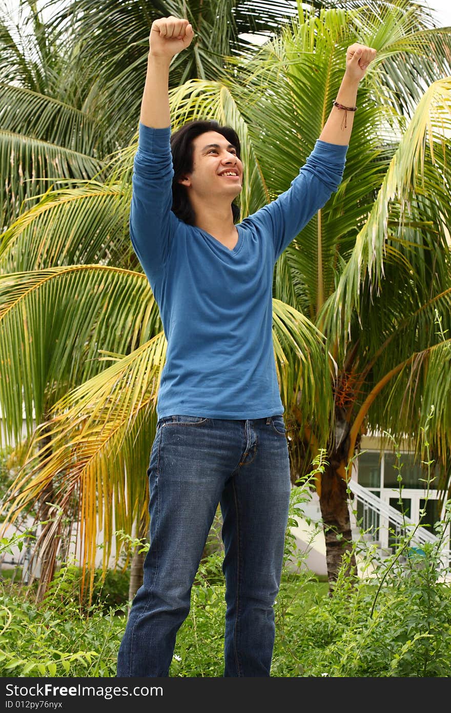 Young man raising his arms in the air as a victorious gesture. Young man raising his arms in the air as a victorious gesture