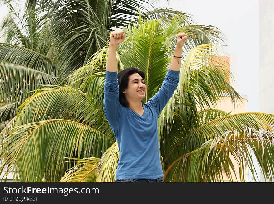 Young man raising his arms in the air as a victorious gesture. Young man raising his arms in the air as a victorious gesture