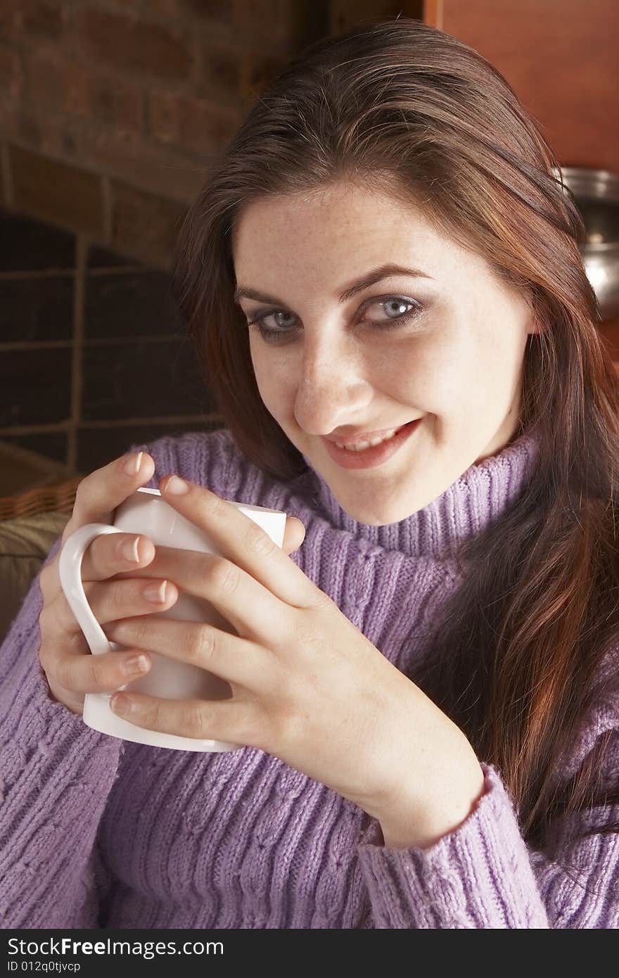 Smiling young girl with long brown hair holding white mug with both hands dressed in purple jersey. Smiling young girl with long brown hair holding white mug with both hands dressed in purple jersey