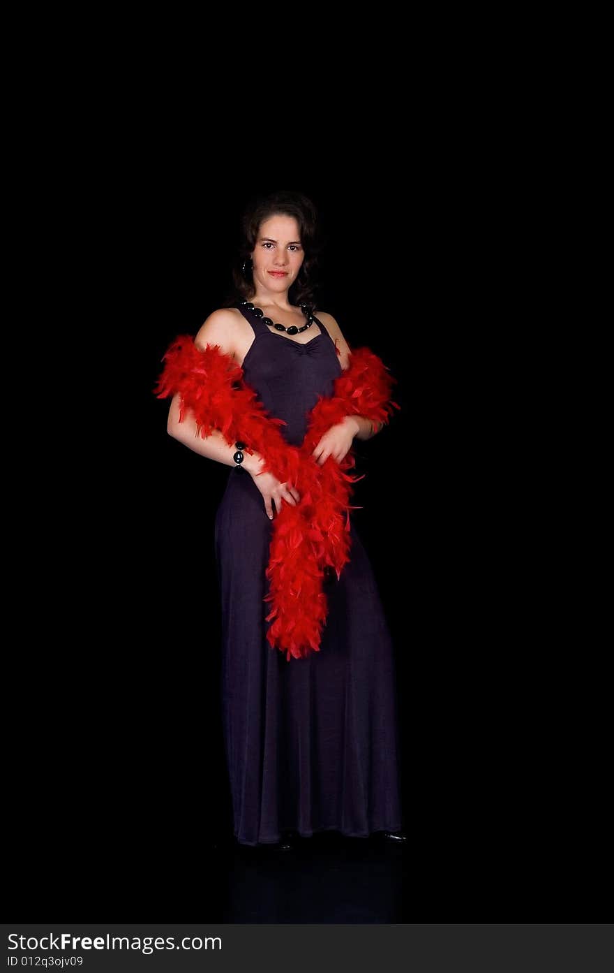 Glamorous young lady with purple dress and red boa on black background, studio shot