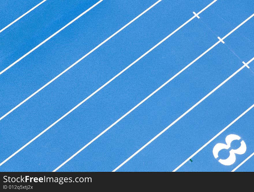 A photograph the lanes of a blue, quarter mile race track from above