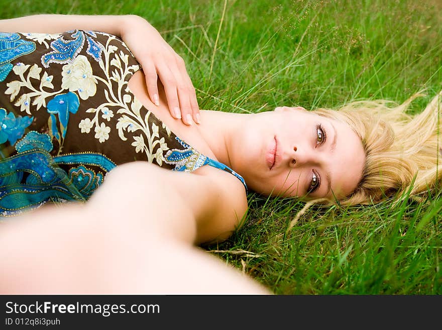 Young beautiful blond girl laying down on the green grass. Young beautiful blond girl laying down on the green grass