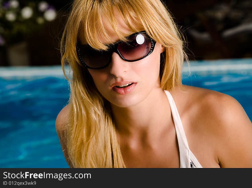 Young blond girl enjoying the sun in and around the swimming pool. Young blond girl enjoying the sun in and around the swimming pool