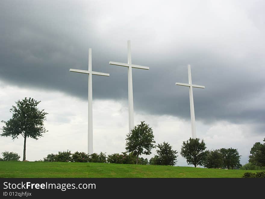 Three (3) huge white crosses on a hill against a cloudy sky. Three (3) huge white crosses on a hill against a cloudy sky