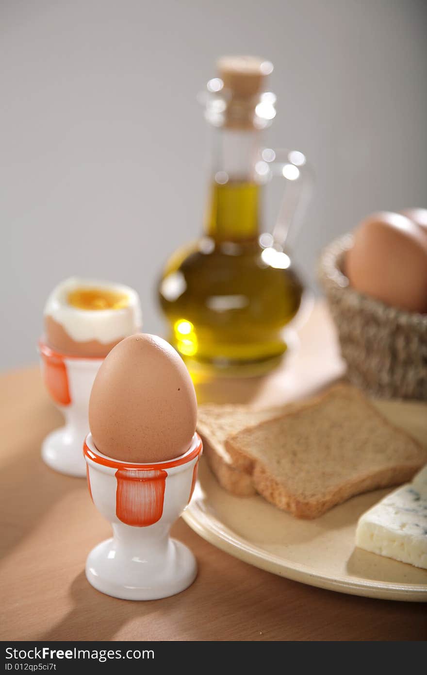 Breakfast table with toast bread and boiled eggs in cups in blur with windows reflections in the background. Breakfast table with toast bread and boiled eggs in cups in blur with windows reflections in the background.