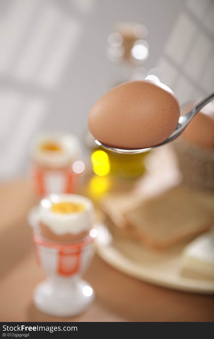 Breakfast table with toast bread and boiled eggs in cups in blur with windows reflections in the background. Breakfast table with toast bread and boiled eggs in cups in blur with windows reflections in the background.