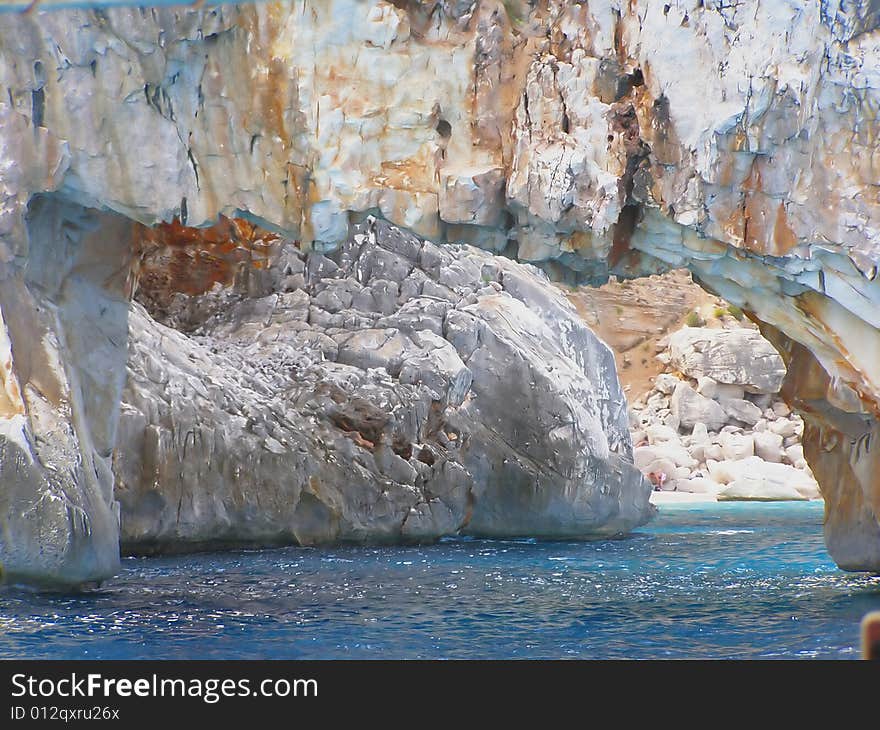 Cala Goloritze in Sardinia - Italy detail: view of beautiful stretch of white pebbles through natural arch the sea. Cala Goloritze in Sardinia - Italy detail: view of beautiful stretch of white pebbles through natural arch the sea