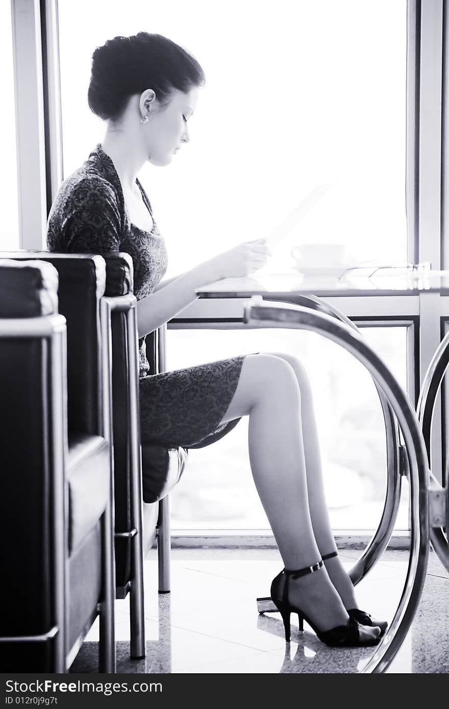 A young woman sitting at the table with a cup of coffee. A young woman sitting at the table with a cup of coffee