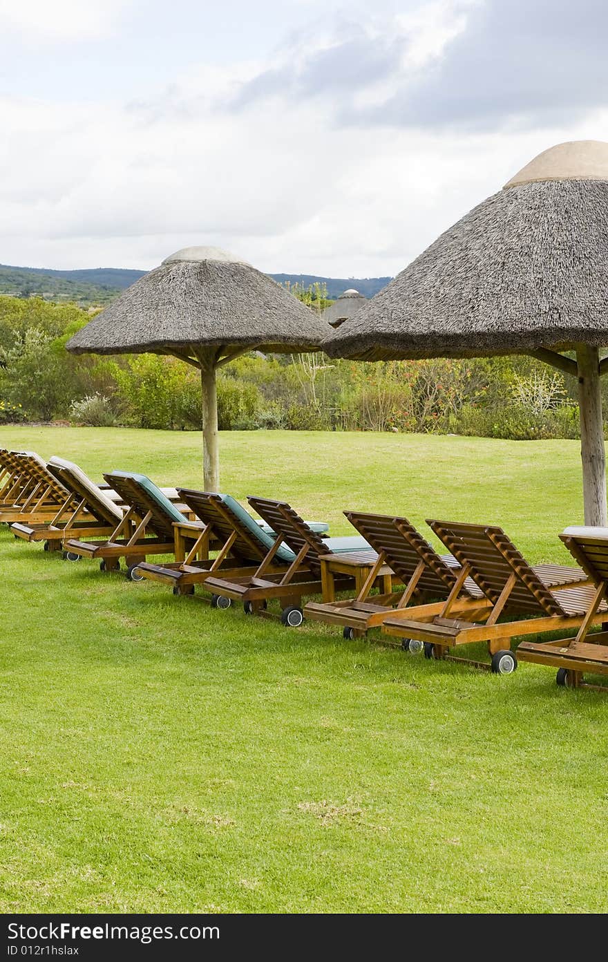 Beautiful lush garden on a farm in the countryside. Some deck-chairs are set on grass near a swimming pool. Beautiful lush garden on a farm in the countryside. Some deck-chairs are set on grass near a swimming pool.