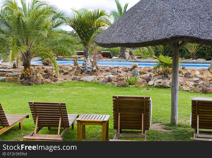 Beautiful lush garden on a farm in the countryside. Some deck-chairs are set on grass near a swimming pool. Beautiful lush garden on a farm in the countryside. Some deck-chairs are set on grass near a swimming pool.