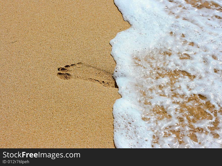 Footprint on sand and sea foam. Footprint on sand and sea foam