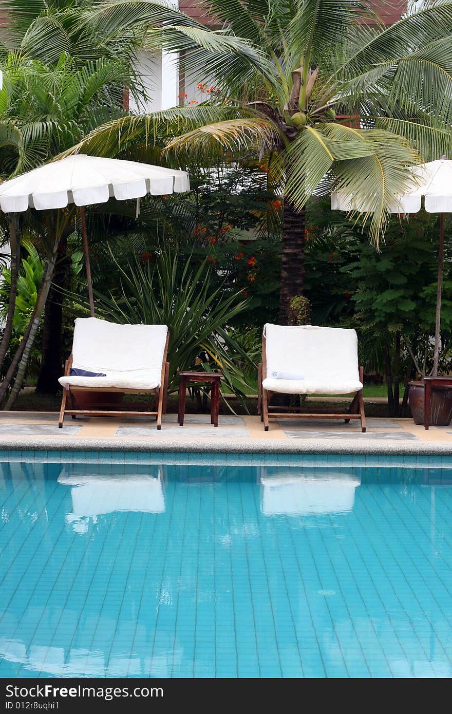 Deck chairs and umbrellas next to a swimming pool.