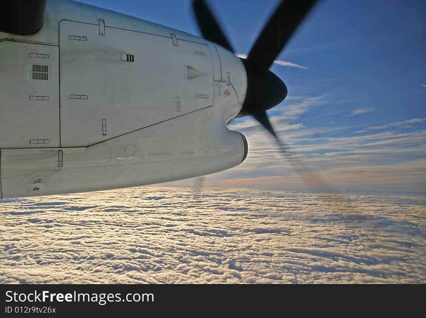 Sunrise appearing above the clouds seen under the engine cowling and propeller of a turboprop aircraft. Sunrise appearing above the clouds seen under the engine cowling and propeller of a turboprop aircraft.