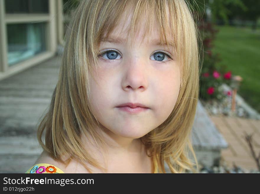 Head shot of little girl sitting outdoors with thoughtful look on face. Head shot of little girl sitting outdoors with thoughtful look on face