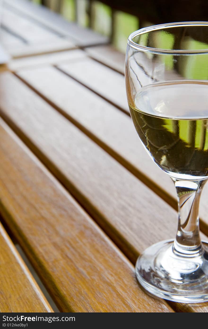 Glasses of white wine on a wooden table at an outside restaurant on a cloudy day in the countryside. Glasses of white wine on a wooden table at an outside restaurant on a cloudy day in the countryside.