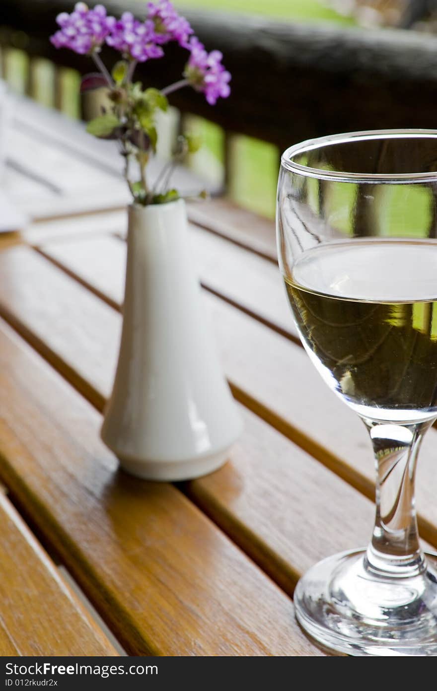 Glasses of white wine on a wooden table at an outside restaurant on a cloudy day in the countryside. Glasses of white wine on a wooden table at an outside restaurant on a cloudy day in the countryside.