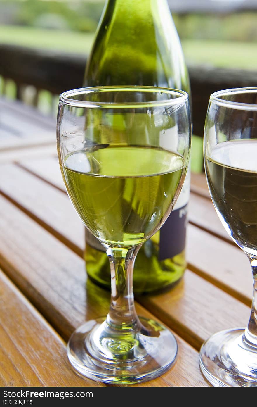 Glasses of white wine on a wooden table at an outside restaurant on a cloudy day in the countryside. Glasses of white wine on a wooden table at an outside restaurant on a cloudy day in the countryside.