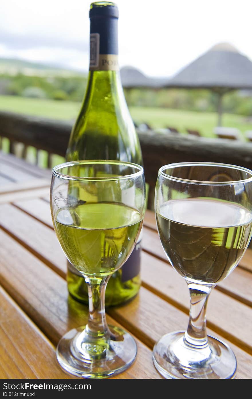 Glasses of white wine on a wooden table at an outside restaurant on a cloudy day in the countryside. Glasses of white wine on a wooden table at an outside restaurant on a cloudy day in the countryside.