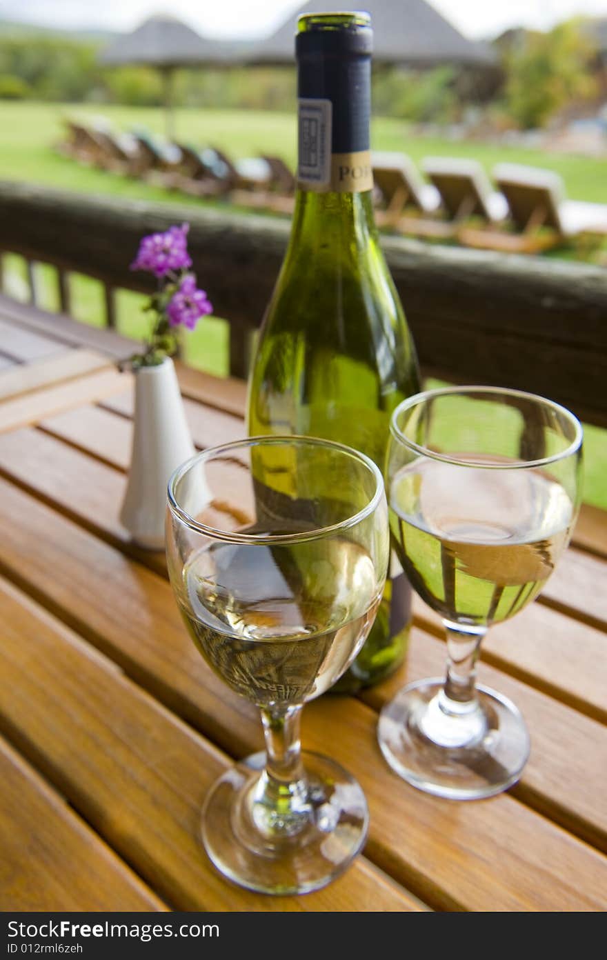 Glasses of white wine on a wooden table at an outside restaurant on a cloudy day in the countryside. Glasses of white wine on a wooden table at an outside restaurant on a cloudy day in the countryside.