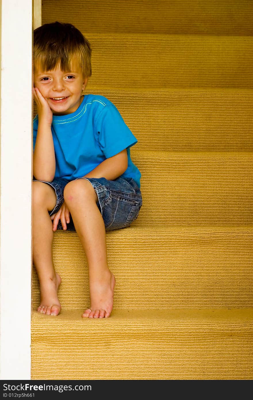 Happy Little Boy sitting on the stairs. Some copyspace to the right.