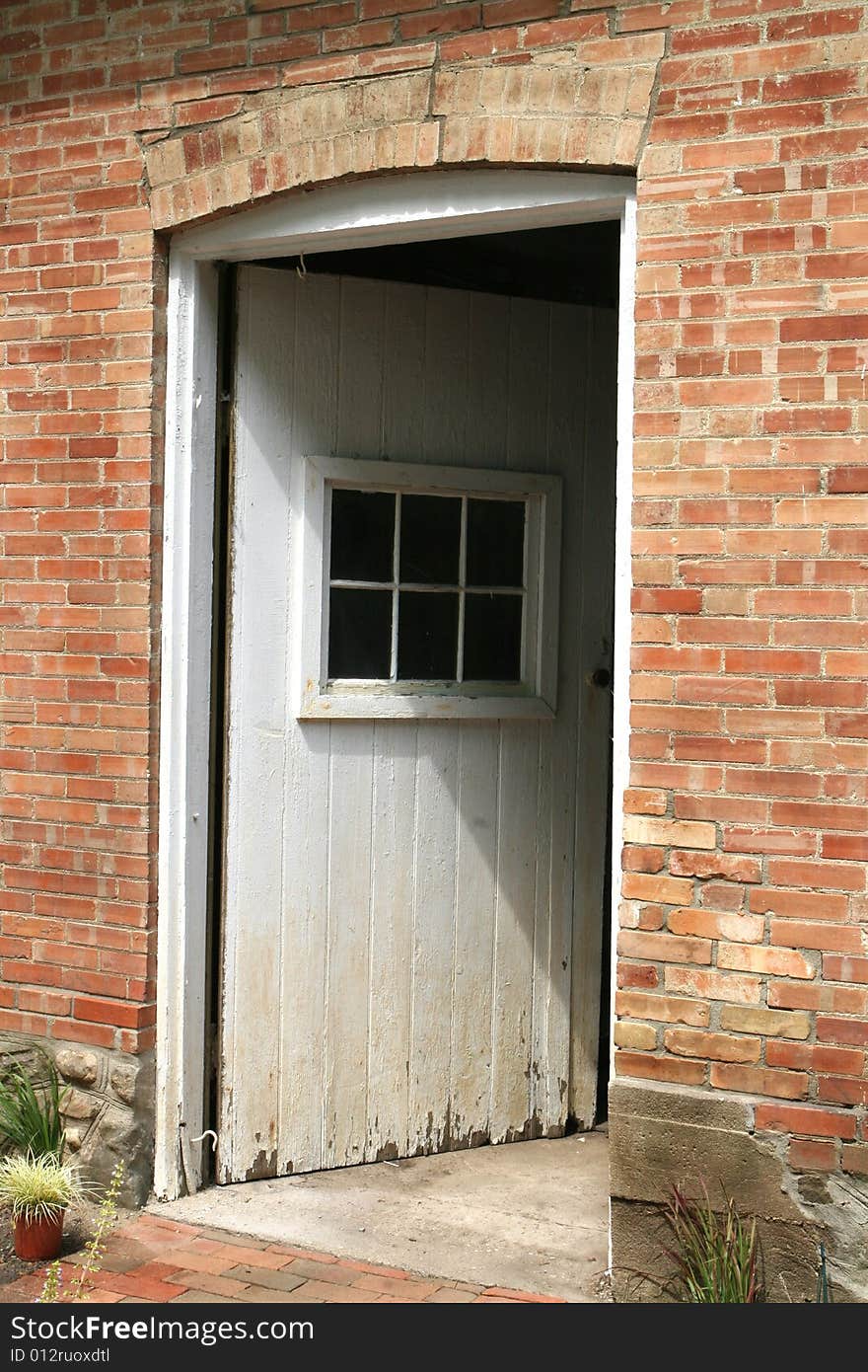 White door adjar in rust color brick wall. White door adjar in rust color brick wall