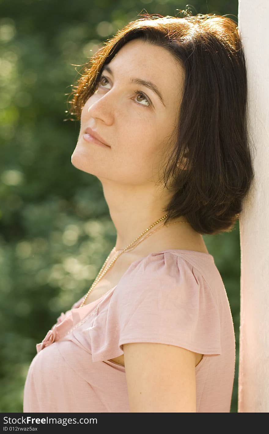 Portrait of dreaming pretty woman standing near white column