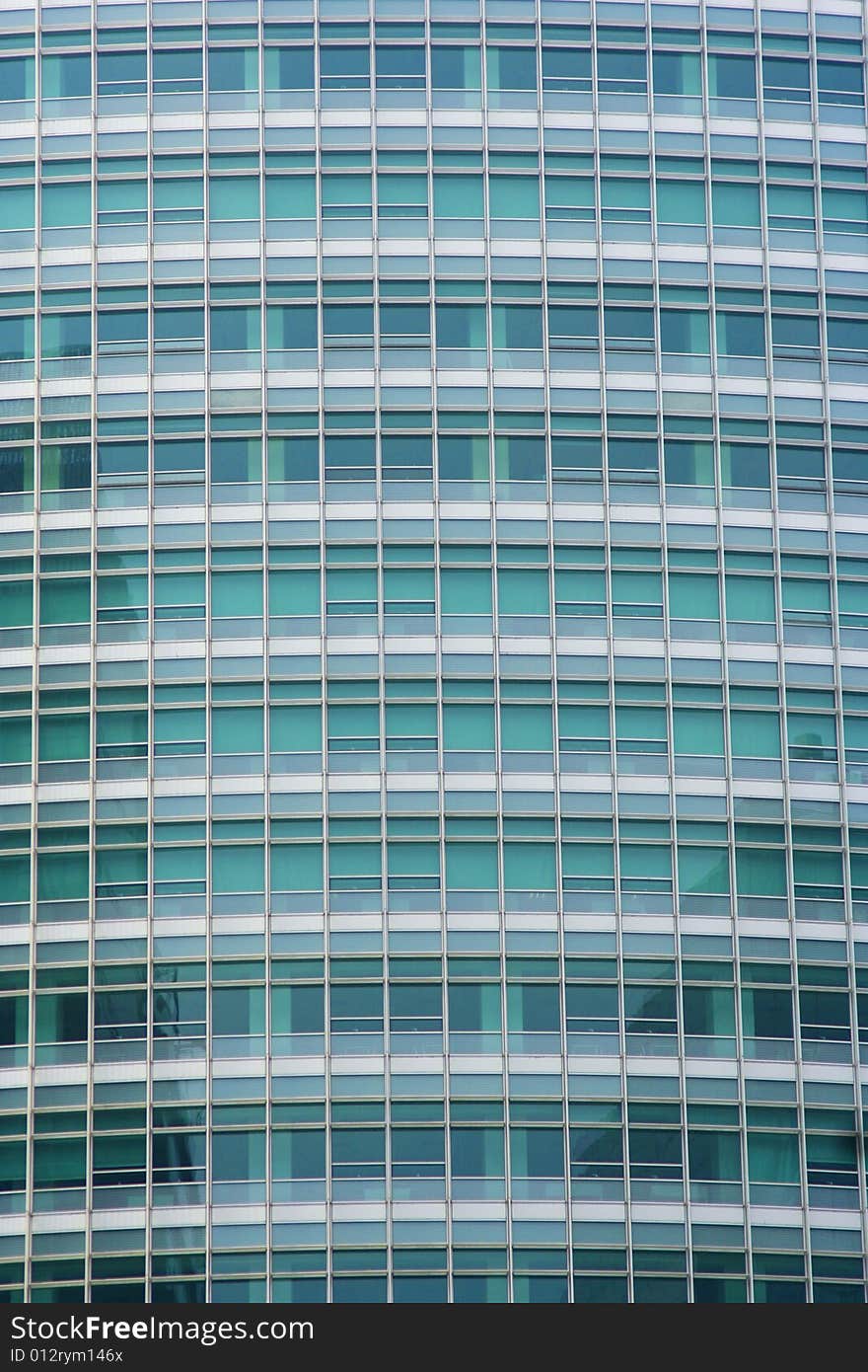 Full frame of a modern office building with transparent greenish windows.