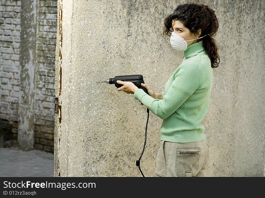 Woman wearing a mask using an electric sander. Horizontally framed photo. Woman wearing a mask using an electric sander. Horizontally framed photo.