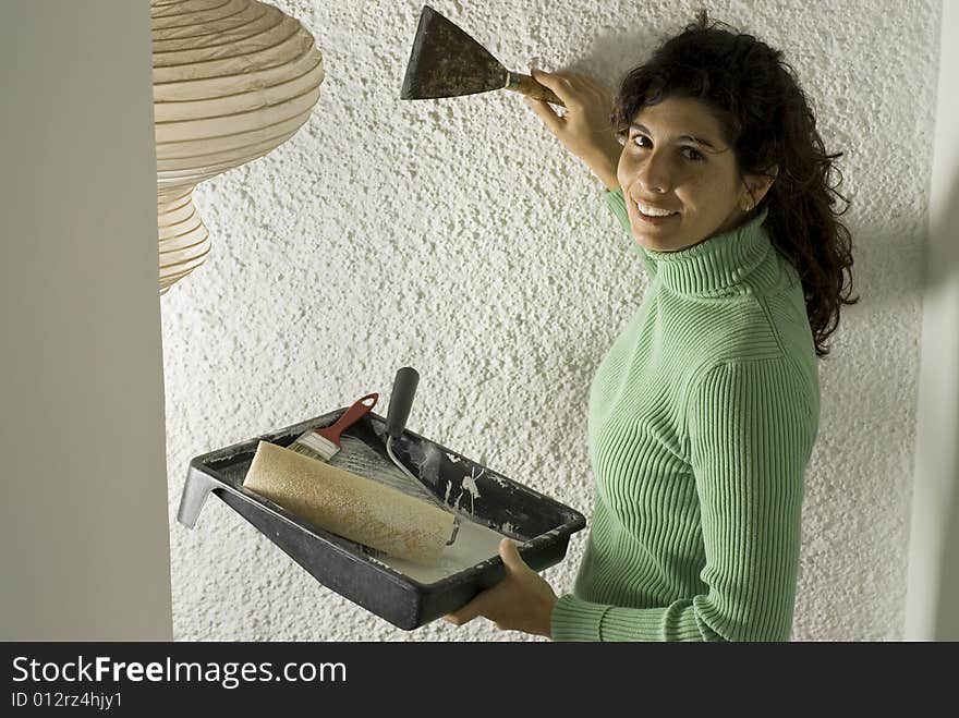 Woman smiles as she holds a paint tray and a paint scraper. Vertically framed photo. Woman smiles as she holds a paint tray and a paint scraper. Vertically framed photo.