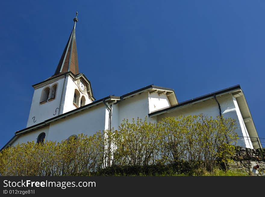 The church in the Swiss wine-growing village of Fechy, from a low viewpoint. Space for text in the clear blue sky. The church in the Swiss wine-growing village of Fechy, from a low viewpoint. Space for text in the clear blue sky.