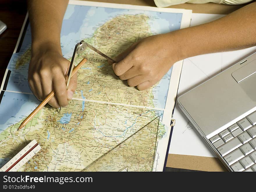 Hands using a protractor, map, and a laptop computer. Horizontally framed photograph. Hands using a protractor, map, and a laptop computer. Horizontally framed photograph.