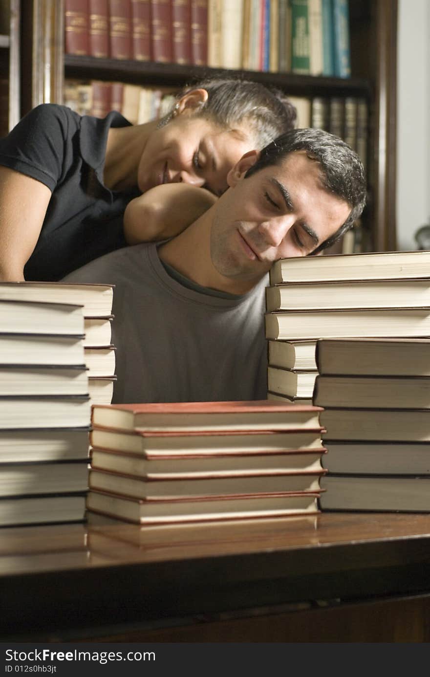 Young couple asleep on a pile of books. Vertically framed photograph. Young couple asleep on a pile of books. Vertically framed photograph.