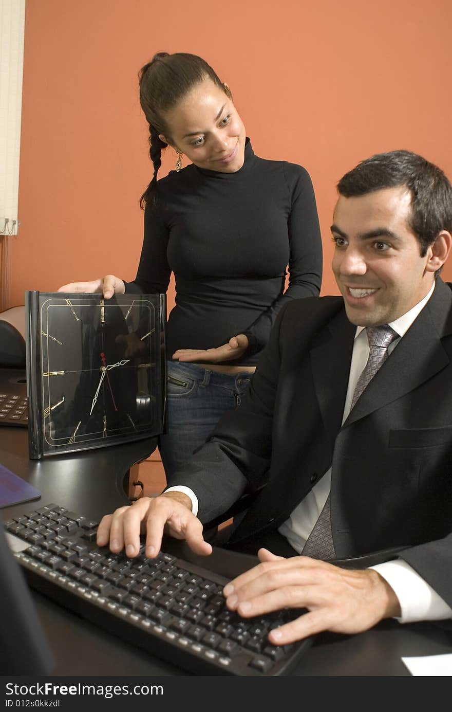 Businessman typing as his secretary looks on. Vertically framed photo. Businessman typing as his secretary looks on. Vertically framed photo.