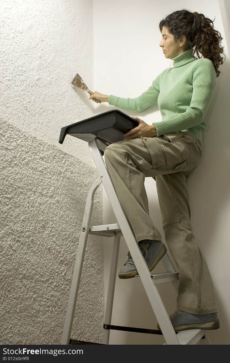 Woman standing on a ladder uses a paint scraper. Vertically framed photo. Woman standing on a ladder uses a paint scraper. Vertically framed photo.