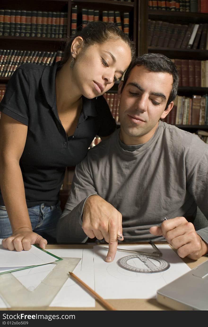 Young couple with their heads pressed together work on paperwork. Vertically framed photograph. Young couple with their heads pressed together work on paperwork. Vertically framed photograph.