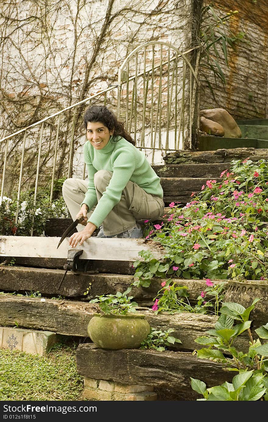 Smiling woman crouching on the steps cutting a piece of wood. Vertically framed photo. Smiling woman crouching on the steps cutting a piece of wood. Vertically framed photo.