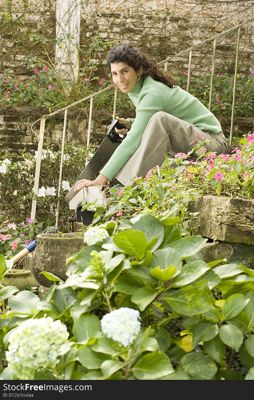 Smiling woman crouching on the steps cutting a piece of wood. Vertically framed photo. Smiling woman crouching on the steps cutting a piece of wood. Vertically framed photo.