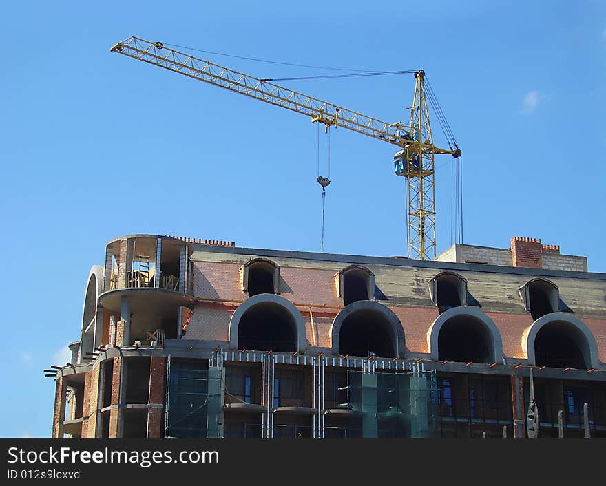 Construction of modern building in big city. Building and crane on a background of summer blue sky. Construction of modern building in big city. Building and crane on a background of summer blue sky.