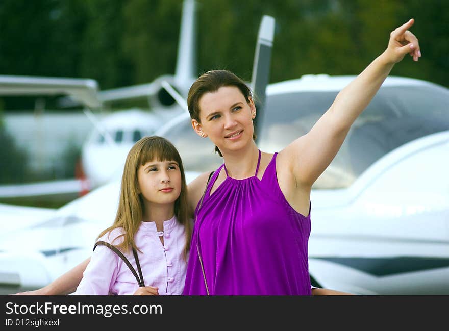 Mother looking daughter to airplane on front view. Mother looking daughter to airplane on front view.