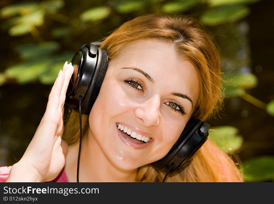 Beautiful young woman listen music by headphones in natural environment. Beautiful young woman listen music by headphones in natural environment.