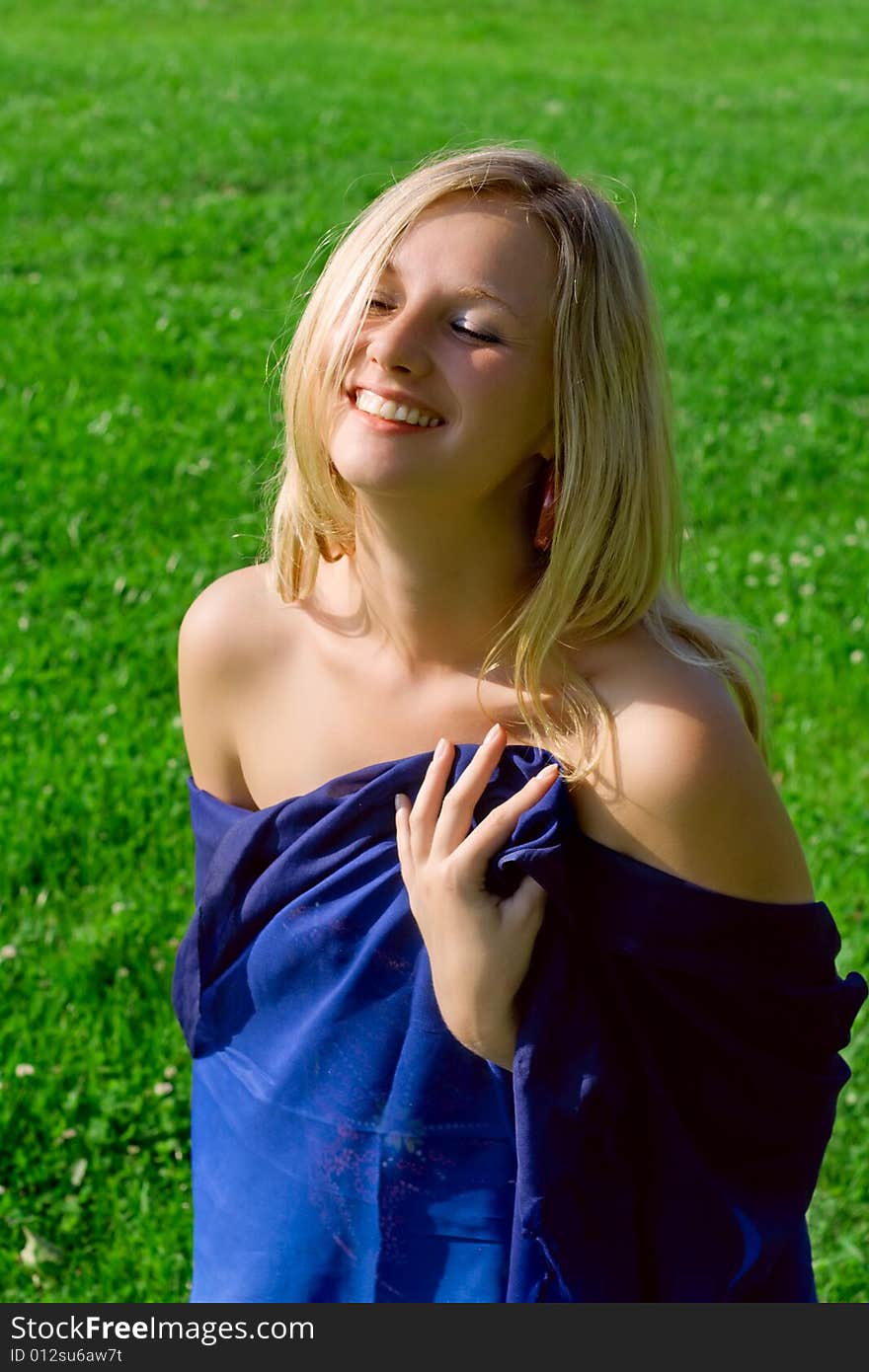 Blond girl laughter against a background green grass