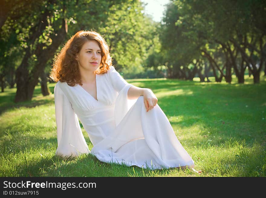 Young woman sit on meadow in garden. Young woman sit on meadow in garden